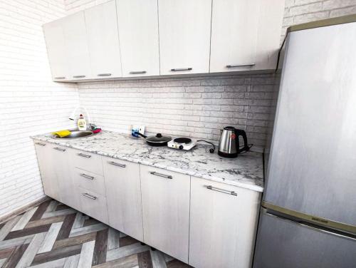 a kitchen with white cabinets and a marble counter top at Апартаменты в новостройке по Байзакова 131/1 in Pavlodar