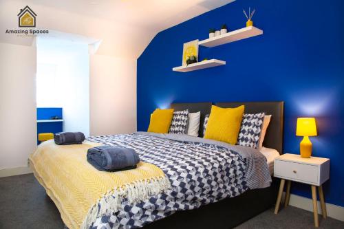 Dormitorio azul con cama y pared azul en LARGE UNIQUE 2 BEDROOM DUPLEX APARTMENT WITH PRIVATE PARKING & FREE WIFI - VAT QUALIFYING BY AMAZING SPACES RELOCATIONS Ltd en Warrington