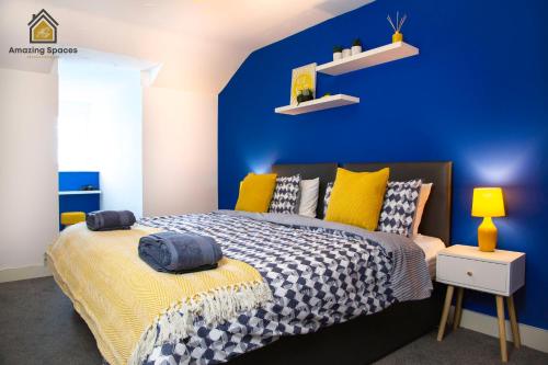 ein blaues Schlafzimmer mit einem Bett und einer blauen Wand in der Unterkunft LARGE UNIQUE 2 BEDROOM DUPLEX APARTMENT WITH PRIVATE PARKING & FREE WIFI - VAT QUALIFYING BY AMAZING SPACES RELOCATIONS Ltd in Warrington