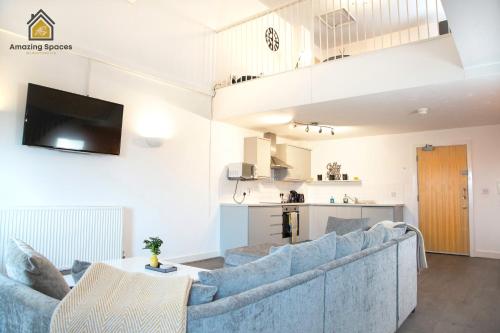 a living room with a blue couch and a kitchen at LARGE UNIQUE 2 BEDROOM DUPLEX APARTMENT WITH PRIVATE PARKING & FREE WIFI - VAT QUALIFYING BY AMAZING SPACES RELOCATIONS Ltd in Warrington