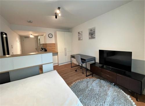 sala de estar con cama y TV de pantalla plana en helloYOU Apartments, en Ingelheim am Rhein
