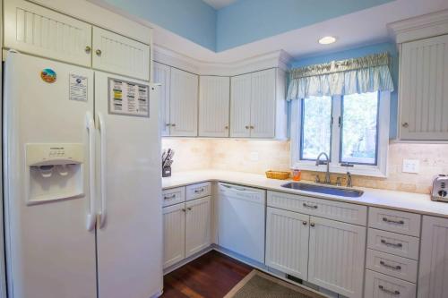 a kitchen with white cabinets and a refrigerator at Surfscoter in Johns Island