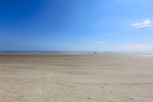 an empty beach with people walking on the sand at Surfscoter in Johns Island
