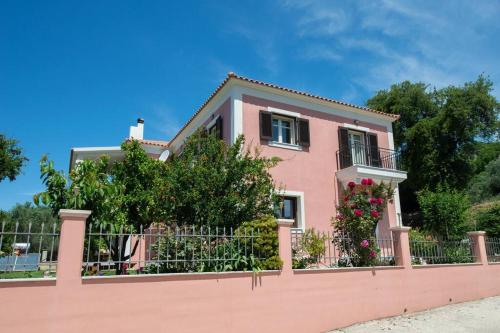 uma casa rosa atrás de uma cerca rosa em Amaryllis 1-Svoronata Village em Svoronata