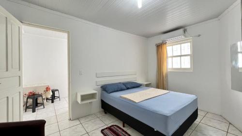 Habitación blanca con cama y ventana en kitnet Revitalize I, en Torres