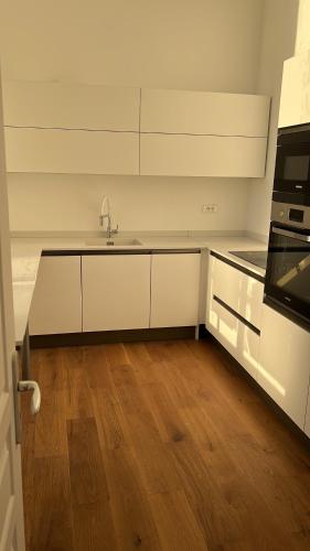 a kitchen with white cabinets and a wooden floor at Appartement château de Lewarde in Douai