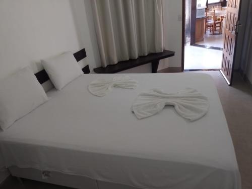 a white bed with a bow tie on it at Hotel Porto Brasília in Porto Seguro