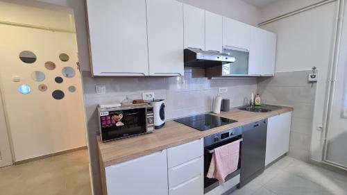 a kitchen with white cabinets and a microwave at Apartment Una in Bjelovar