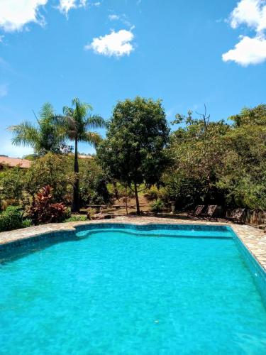 a swimming pool with blue water and trees at Catavento Pousada in Alto Paraíso de Goiás