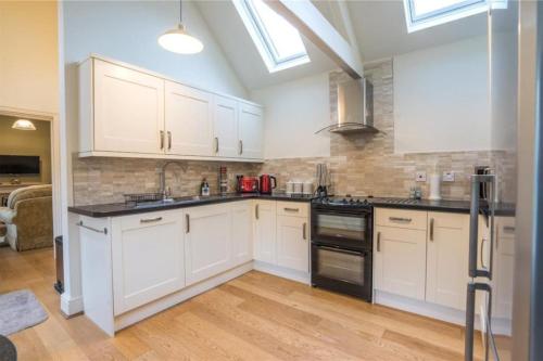 a kitchen with white cabinets and black appliances at Maristow Cottages, overlook Tamar Valley Dartmoor in Plymouth