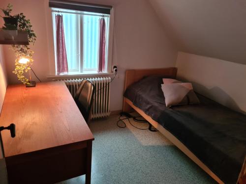 a small bedroom with a bed and a wooden table at Hyggeligt gammelt hus i Vestmanna in Vestmanna