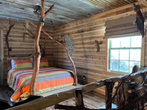 ein Schlafzimmer mit einem Bett in einem Blockhaus in der Unterkunft "Magical Treehouse" w spiral slide off the deck 350 acres on the Brazos River! Tubing! Petting Zoo! in Weatherford