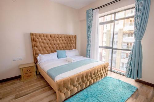 een slaapkamer met een groot bed en een groot raam bij Lathembo Serviced Apartments in Nairobi