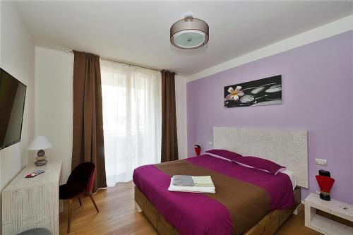 a bedroom with a purple bed and a window at Bed & go Trento in Trento