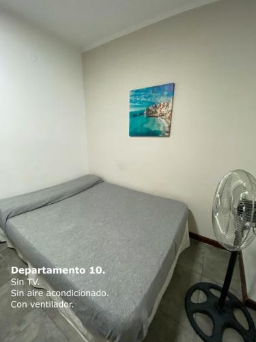 a small bedroom with a bed and a fan at Sarmiento Monoambiente in Concordia