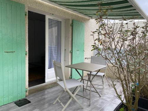 een tafel en stoelen op de patio van een huis bij Au cœur de la Cotinière Studio en résidence parking privé wifi in La Cotinière