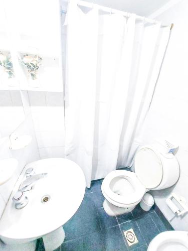 a white bathroom with a toilet and a sink at Departamento DERQUI en la mejor zona de NVA CBA in Cordoba