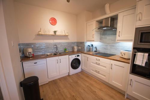 a kitchen with white cabinets and a washing machine at Luxury Penthouse Apartment overlooking Main Beach in Bundoran