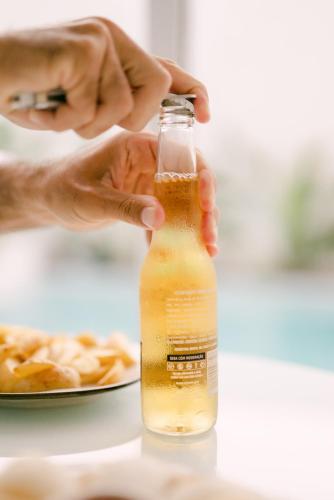 a person holding a bottle of beer with a plate of food at Olisa Hotel Boutique in Maresias