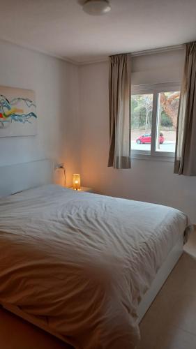 a bedroom with a bed with a lamp and a window at Hacienda Riquelme Golf Resort Groundfloor Apartment 176 in Sucina