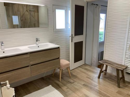 La salle de bains est pourvue d'un lavabo, d'un miroir et d'une chaise. dans l'établissement Maison familiale chaleureuse narbonne, à Narbonne