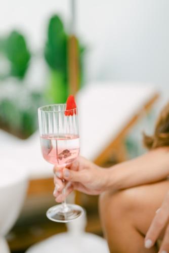 a woman holding a glass with a strawberry in it at Olisa Hotel Boutique in Maresias