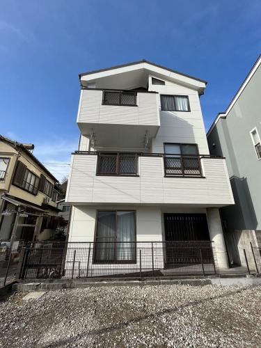 um edifício branco com uma cerca em frente em Kitaizu North Private House - Vacation STAY 14216 em Numazu