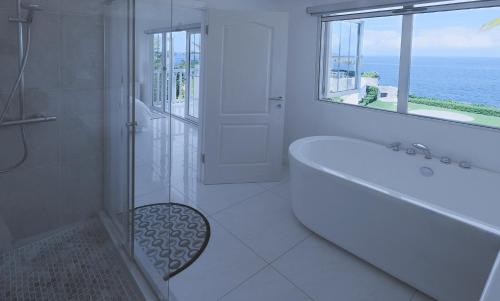 a white bathroom with a tub and a window at Stunning Ocean View in Negril