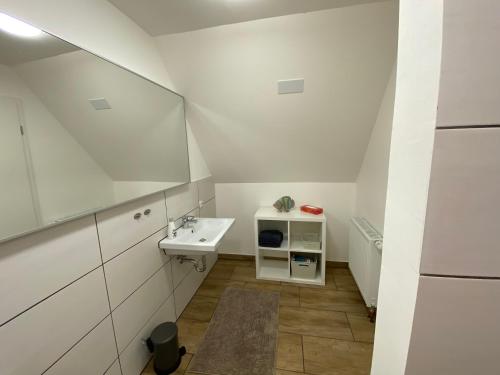 a white bathroom with a sink and a mirror at Huck’s Ferienhäuser in Borstel