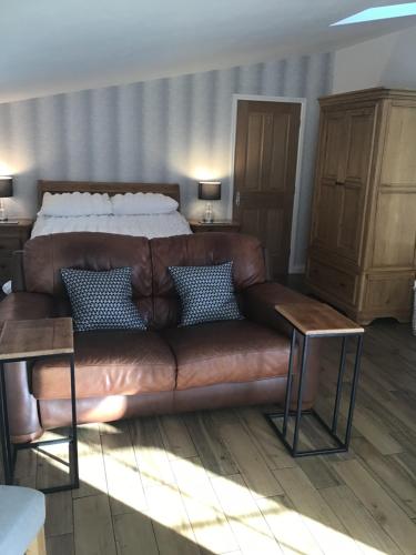 Sofá de cuero marrón en un dormitorio con cama en Garden Suite en Rhuddlan