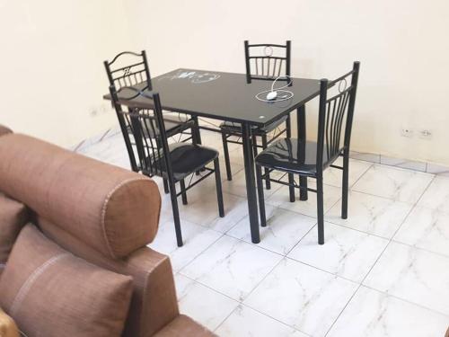 a black dining room table with chairs and a couch at 2 chambres-salon-cuisine-balcons sup 80m2 in Dakar