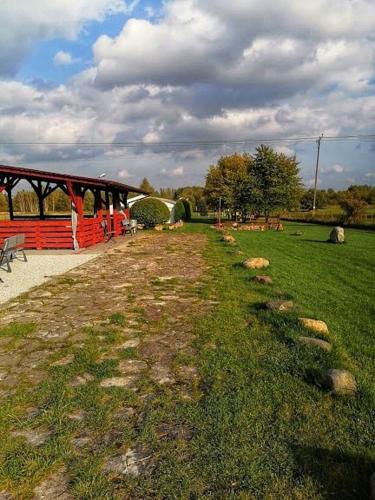 a person standing next to a red train in a field at RJ Hotel in Pabianice