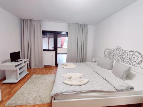 een witte slaapkamer met een bed met een hoed erop bij Penthouse Daniela in Târgu-Mureş