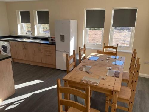 a kitchen with a wooden table with chairs and a refrigerator at Remote Wilderness - sleeps 4 to 6 in Halkirk