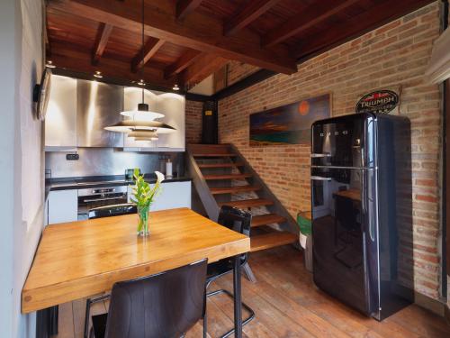 uma cozinha com uma mesa de madeira e um frigorífico preto em Casita de la plaza Lugás em Villaviciosa