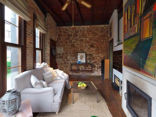 a living room with a white couch and a brick wall at Casita de la plaza Lugás in Villaviciosa