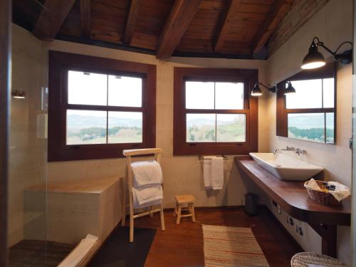 baño con lavabo, silla y ventanas en Casita de la plaza Lugás, en Villaviciosa