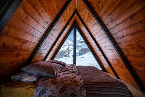 a bed in a room with a large window at Voyager in Kazbegi