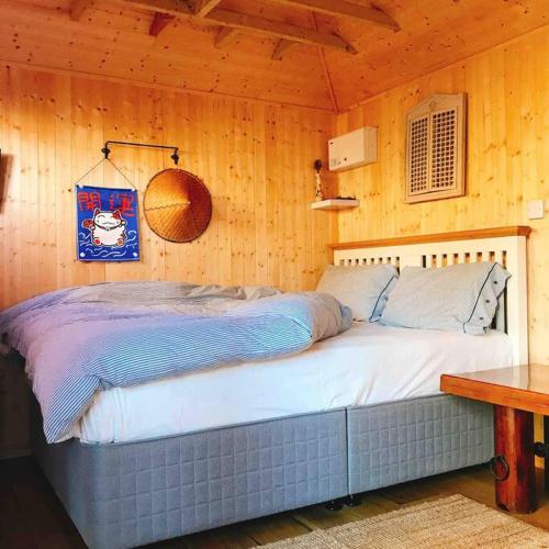 a bedroom with a bed in a wooden wall at Cosy Private Cabin with parking in good location in Oxford
