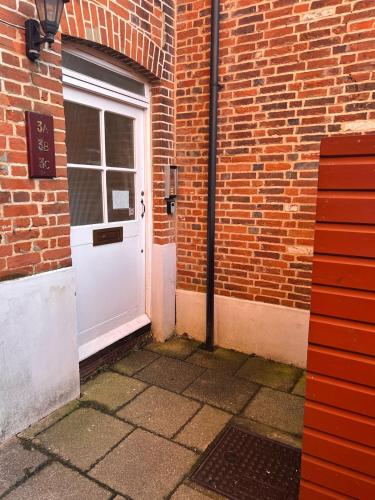 a white door in a brick building with a brick wall at The Farthings, Romsey Apartment in Romsey