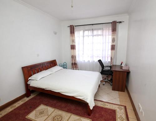 a bedroom with a bed and a desk and a window at Star Luxury Home, Jade Apartments in Nairobi