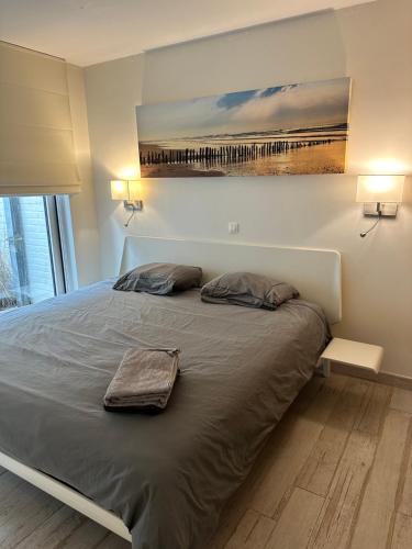 a bed in a bedroom with a painting on the wall at Luxurious and cosy loft - Knokke in Knokke-Heist