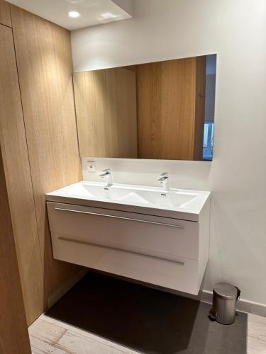 La salle de bains est pourvue d'un lavabo blanc et d'un miroir. dans l'établissement Luxurious and cosy loft - Knokke, à Knokke-Heist