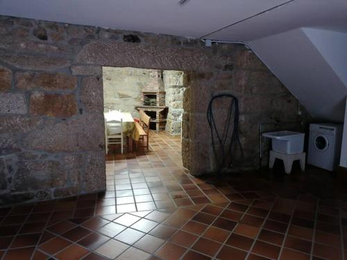a room with a stone wall and a room with a table at O Lar do Suso 