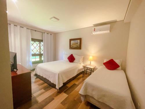 a hotel room with two beds and a television at Pousada Lagos de Minas in Santa Cruz de Minas
