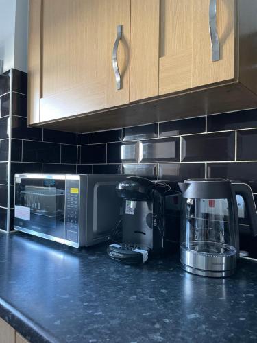 a kitchen counter with a coffee maker and a microwave at Large Comfortable Bed with Own Bathroom Free Parking and Wifi in West Thurrock Grays in Grays Thurrock