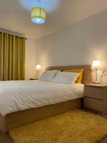 a bedroom with a large bed with two lamps and a rug at Large Comfortable Bed with Own Bathroom Free Parking and Wifi in West Thurrock Grays in Grays Thurrock
