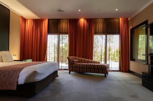 a bedroom with a bed and a couch and windows at Hotel Casino Magic in Neuquén