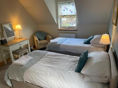 a bedroom with two beds and a desk and a chair at Sidhean Dubha Holiday Home in Portree