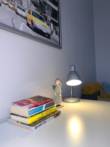 ein Stapel Bücher, die auf einem Tisch neben einer Lampe sitzen in der Unterkunft W Muzycznej Dzielnicy in Bydgoszcz